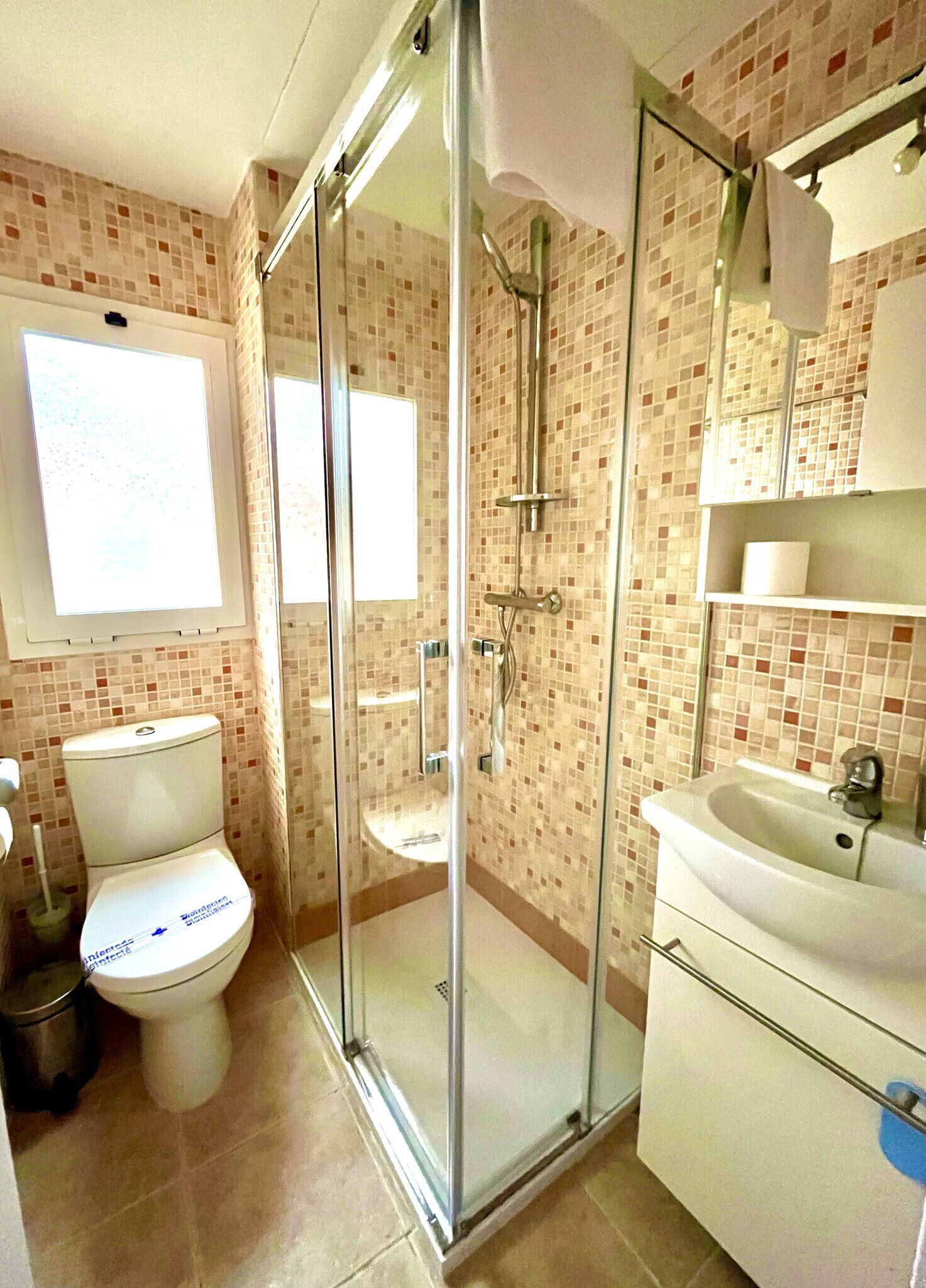 Un baño con ducha envuelta en vidrio, inodoro y lavamanos.