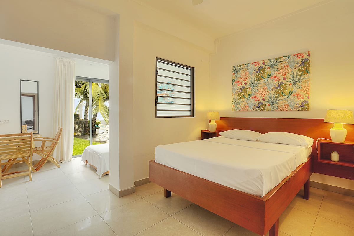 A bedroom with a bed, bedside lamps, a painting, and a view of the outdoors.