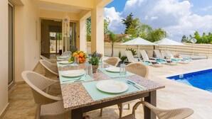 Un espace extérieur aménagé pour les repas, avec une piscine, des chaises en osier et une table dressée pour deux personnes.