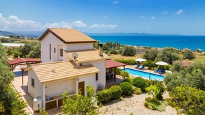 A two-story house with a swimming pool, surrounded by greenery and a view of the sea. - Villa Erato - Three Bedroom Villa, Sleeps 6 (Nea Dimmata)