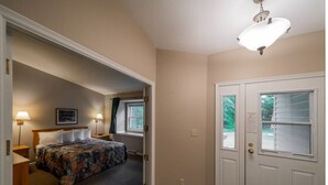 A hotel room with a bed, bedside lamps, a door, and a window. - Lakefront 2BR Condo on Namakagon – Views, Trails, Pontoon Rentals & Fishing! (Cable)