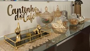 Une cuisine moderne avec une table basse en verre, des objets décoratifs et un panneau indiquant « Cantinho do Café ».