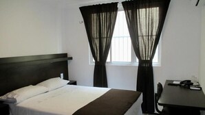 Une chambre d’hôtel avec un lit, un bureau et des rideaux.