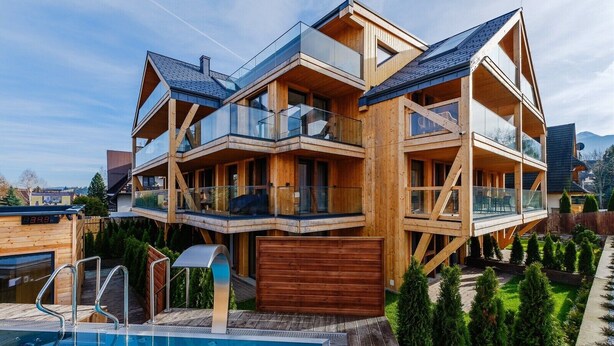 A multi-story wooden house with balconies, a swimming pool, and a well-maintained garden. - Apartament RELAKS (Zakopane)