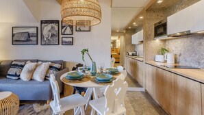 A modern kitchen with wooden cabinets and a dining area with a round table and white chairs. - Apartament RELAKS (Zakopane)