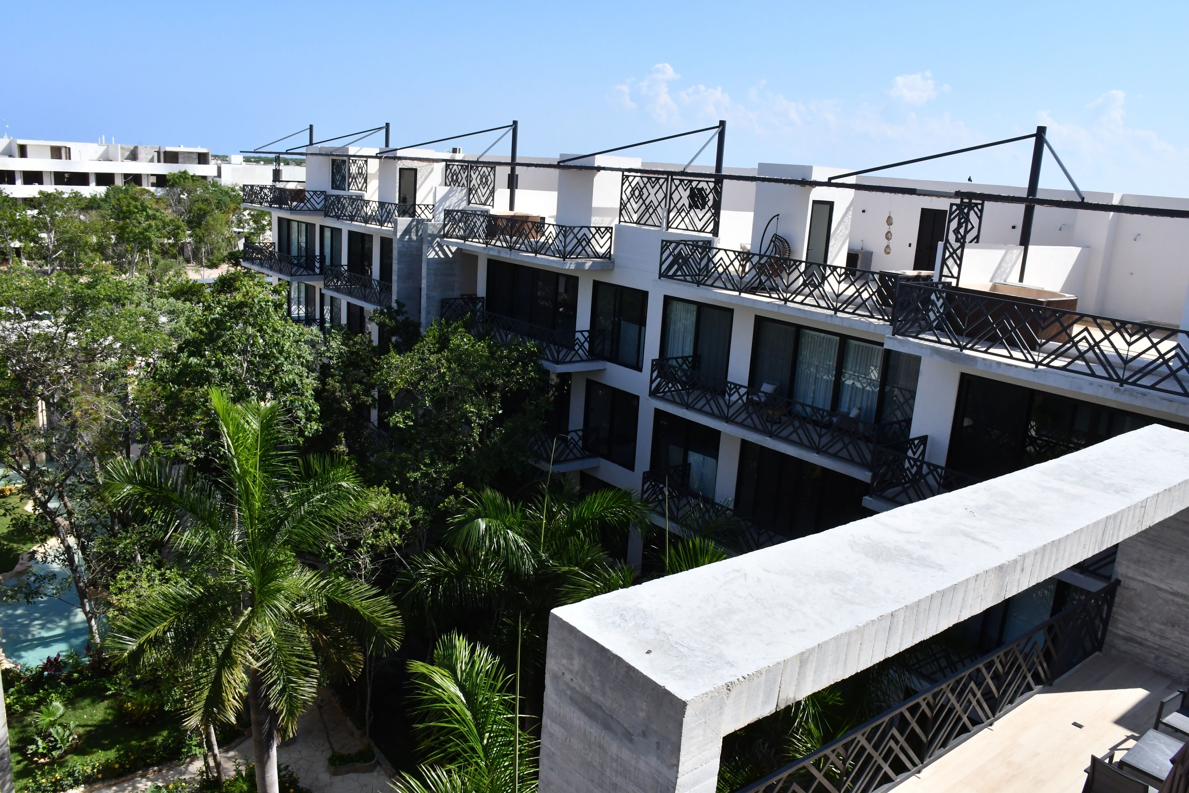 A multi-story hotel with balconies, a pool, and lush greenery.