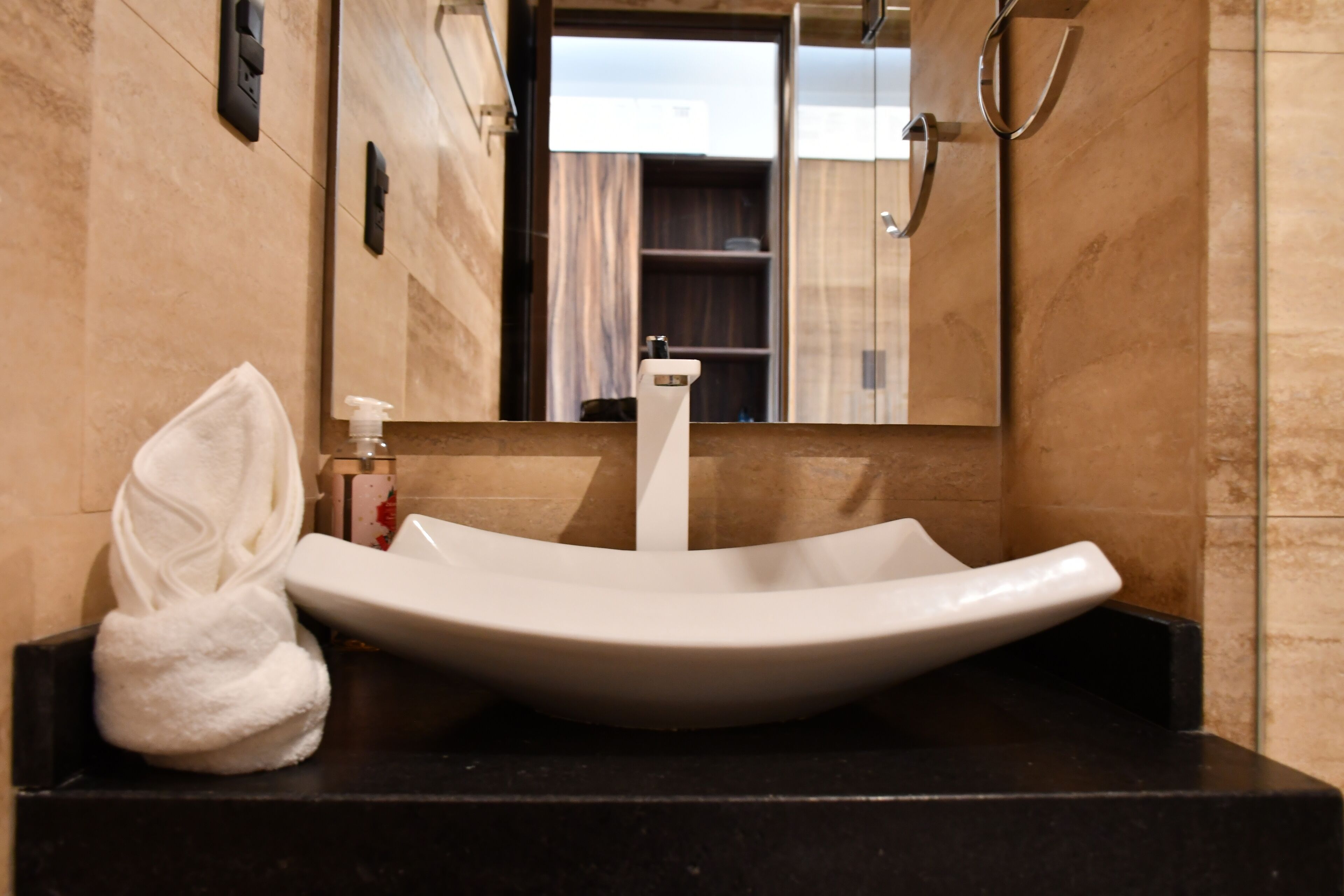 A bathroom with a white vessel sink, a towel, and a mirror reflecting a shower area.