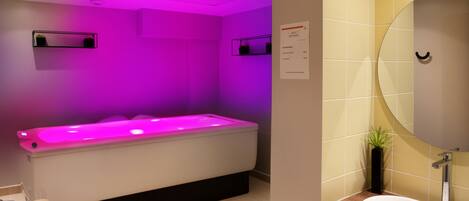 A modern bathroom with a heated floor bath, a sink, and a mirror.