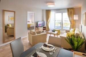 Una habitación de hotel moderna con zona de comedor, sala de estar y balcón.