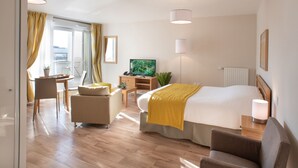 Une chambre d’hôtel équipée d’un lit, d’un bureau, d’une chaise, d’une télévision et d’une fenêtre avec des rideaux.