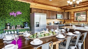 A modern kitchen with wooden cabinets, a stainless steel refrigerator, and a neon sign. - Luxury Views, Sparkling Pool, Giant Theater Oh My! (Sevierville)