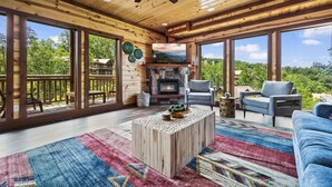 A spacious wooden interior with a fireplace, large windows, and a ceiling fan. - Luxury Views, Sparkling Pool, Giant Theater Oh My! (Sevierville)