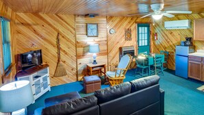 A cozy cabin interior with a wooden interior, a ceiling fan, a television, a fireplace, a dining area, and a kitchen. - 2 Mi to Green Bank Observatory! Mtn-View Cabin (Green Bank)