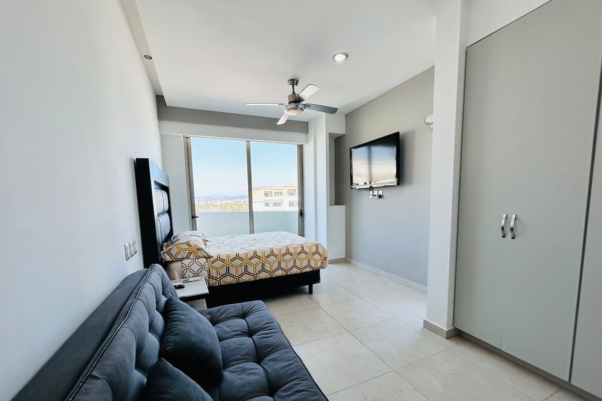A modern bedroom with a bed, a sofa, a TV, and a wardrobe.