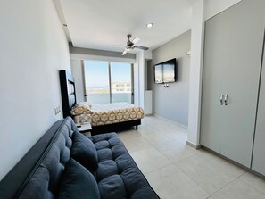 A modern bedroom with a bed, a sofa, a TV, and a wardrobe.