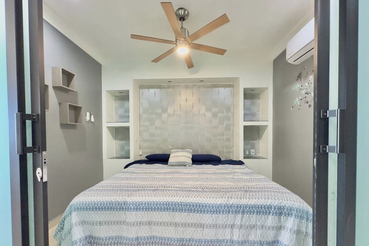 A bedroom with a bed, a ceiling fan, and built-in shelves.