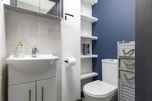 A bathroom with a white sink, a toilet, and a blue accent wall. - c Bright and Spacious House (London)