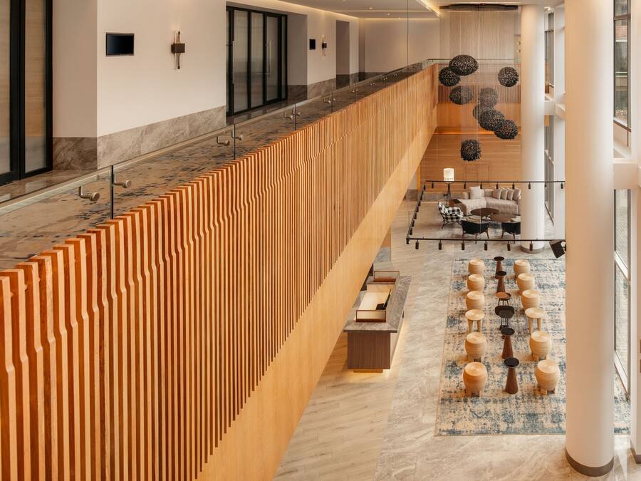 Eine moderne Hotelhalle mit einer langen Rezeption, einer Sitzecke und Blick auf die oberen Stockwerke.