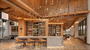 Zona de bar moderna con paneles de madera, una barra central y asientos.
