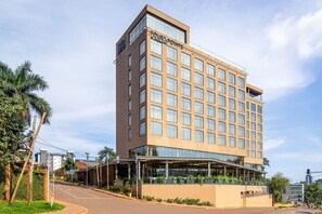 Un hotel moderno con fachada de vidrio, varios pisos y techo plano.