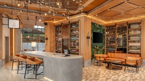 Un espacio moderno de bar con una barra central, taburetes y una zona de estar con sofá y sillas.