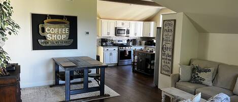 A spacious living area with a dining table, a sofa, and a kitchen in the background.