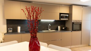 A modern kitchen with a red vase on a white table. - AT WOLF HOUSE, ELEGANT PANORAMIC HOUSE (Cison di Valmarino)