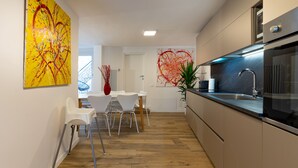 A modern kitchen with a dining area, wooden flooring, and contemporary artwork. - AT WOLF HOUSE, ELEGANT PANORAMIC HOUSE (Cison di Valmarino)