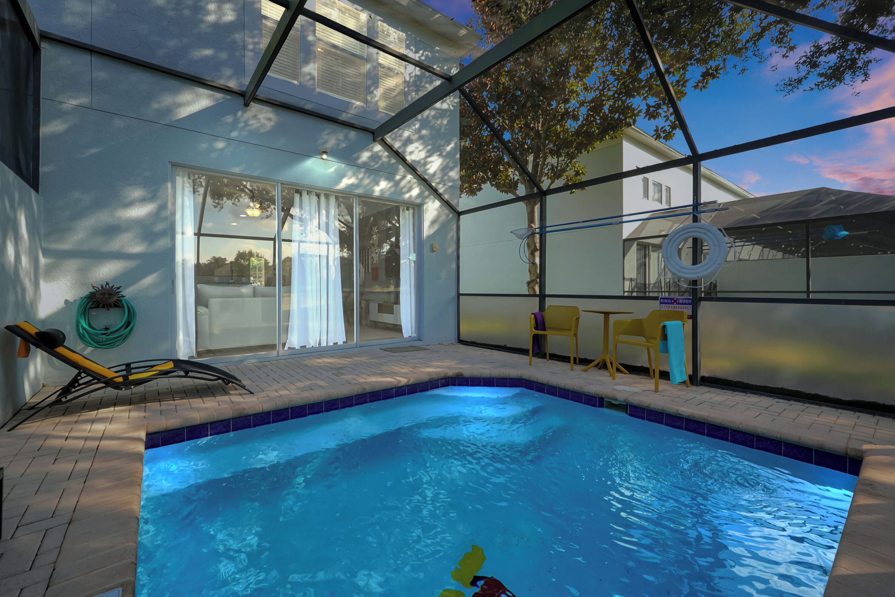 A swimming pool with a tiled edge, a lounge chair, and a hose reel.