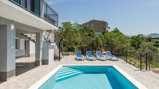 A swimming pool with lounge chairs, a staircase, and a building with balconies. - Vacation House With the Pool, Near River Cetina (Omis)