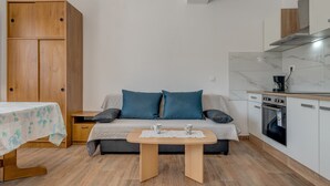 A compact living space with a sofa, a small table, a wooden wardrobe, and a kitchenette. - Vacation House With the Pool, Near River Cetina (Omis)