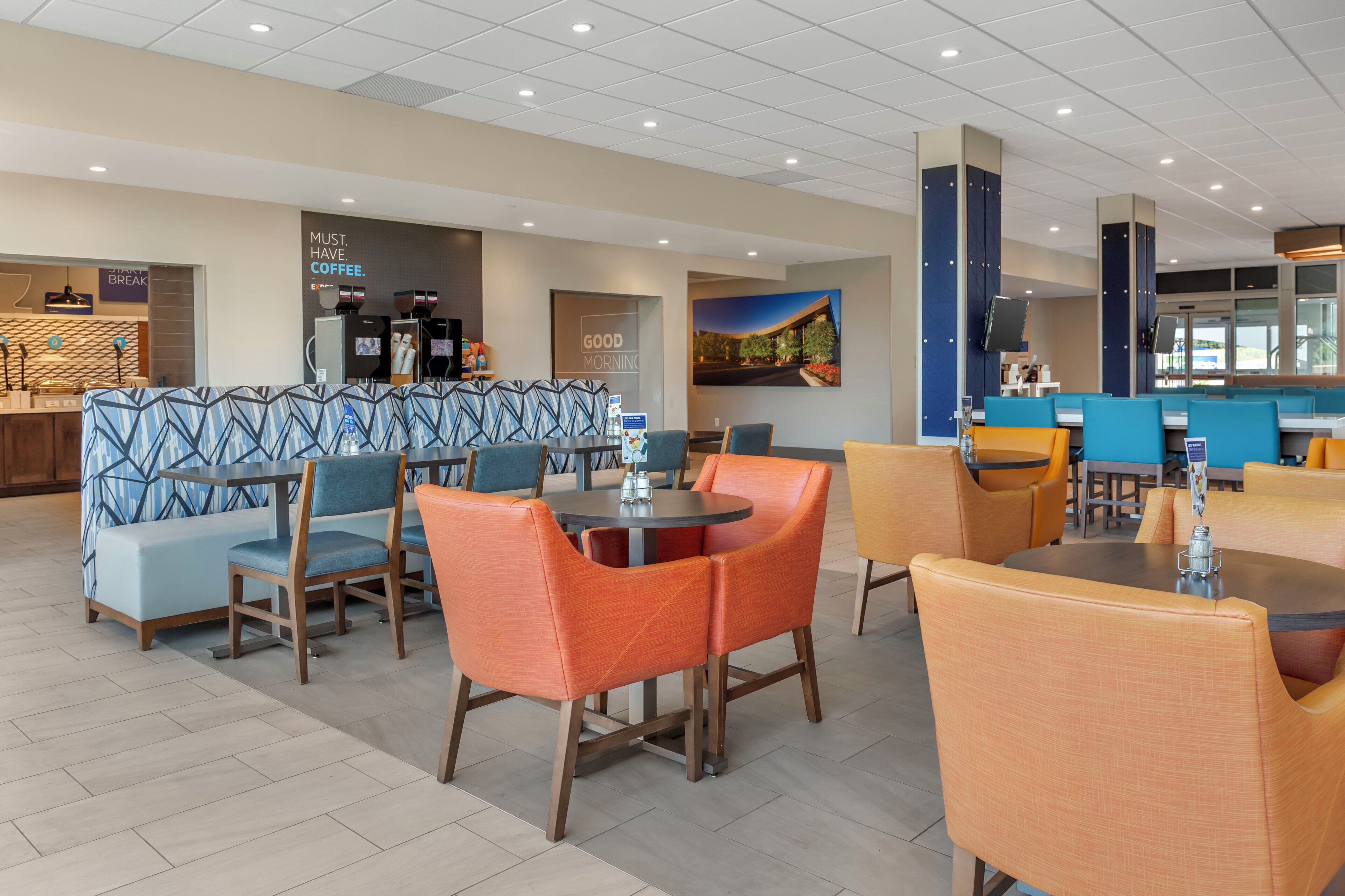 Un moderno vestíbulo de hotel con zonas de estar, una estación de café y vistas al exterior.