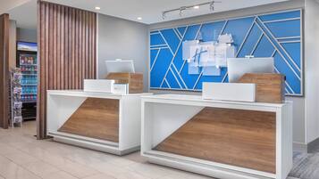 A reception desk with a blue geometric wall design, a vending machine, and a wooden panel.