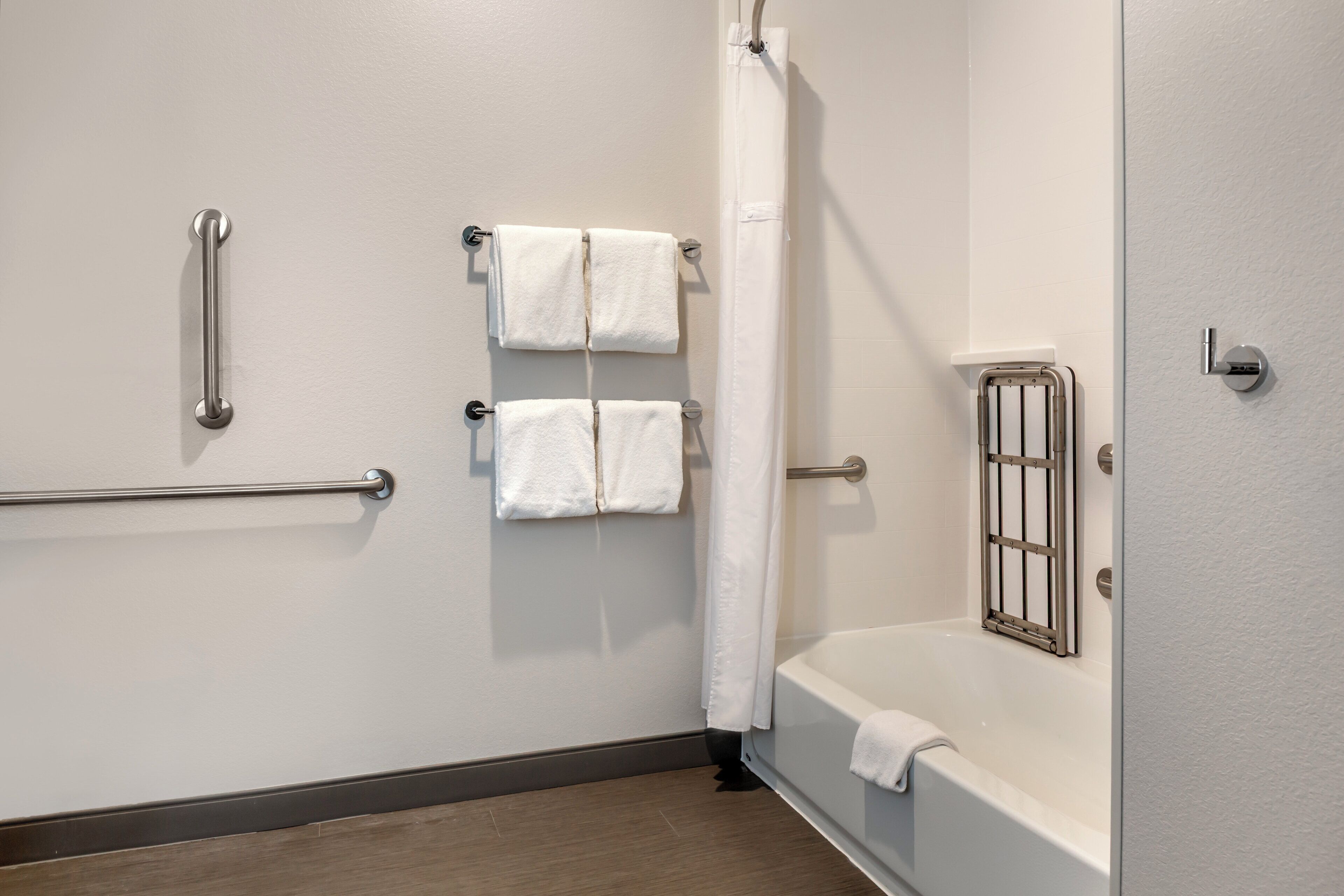 Un baño con bañera, cortina de ducha y dos toalleros con toallas.