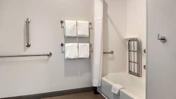 Un baño con bañera, cortina de ducha y dos toalleros con toallas.