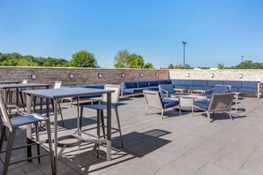 An outdoor patio with tables and chairs, a sofa, and a stone wall. - Holiday Inn Express and Suites Dry Ridge by IHG (Dry Ridge)