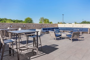 Un patio al aire libre con mesas y sillas, un sofá y un muro de piedra.