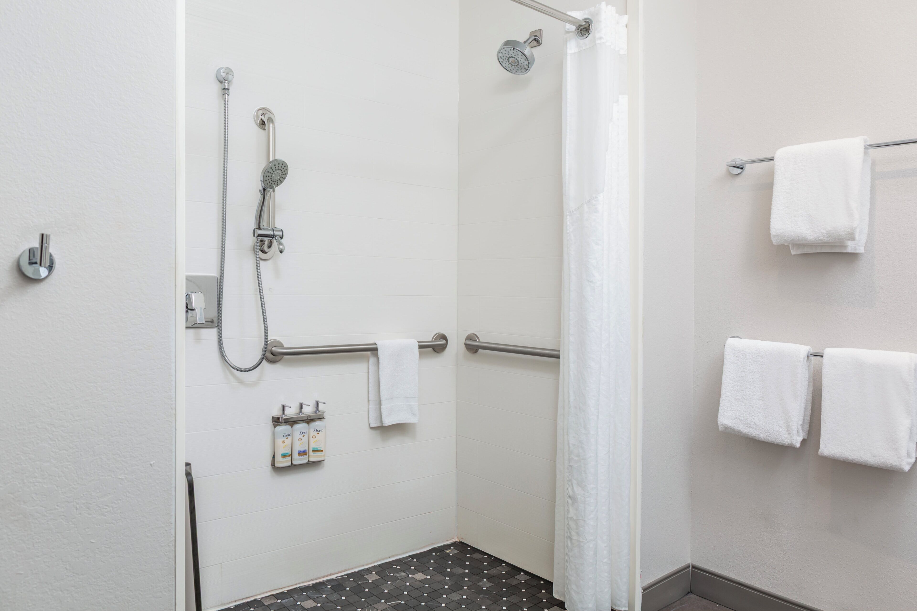 A bathroom with a shower, a towel rack, and toiletries.