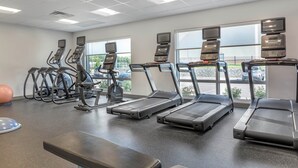 A gym with treadmills, elliptical machines, and a bench.