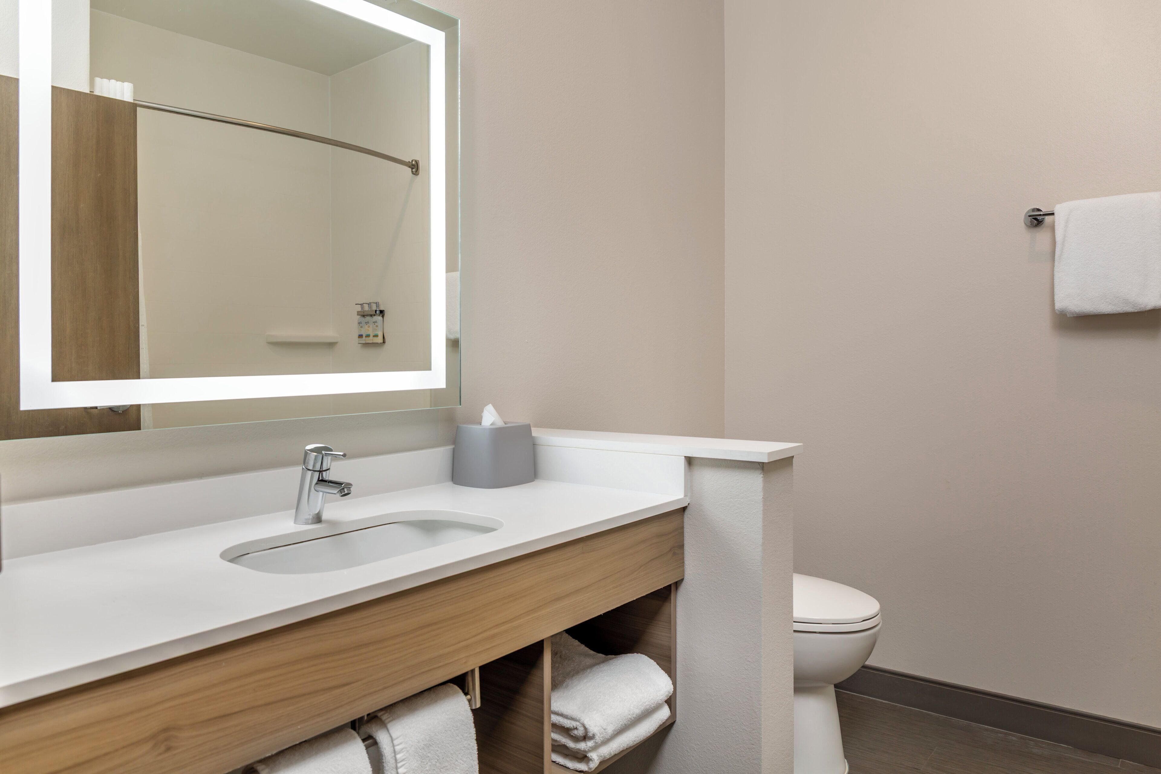 A modern bathroom with a white sink, a mirror, a towel rack, and a toilet.