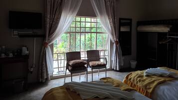 A hotel room with a bed, a chair, a television, and a window with curtains.