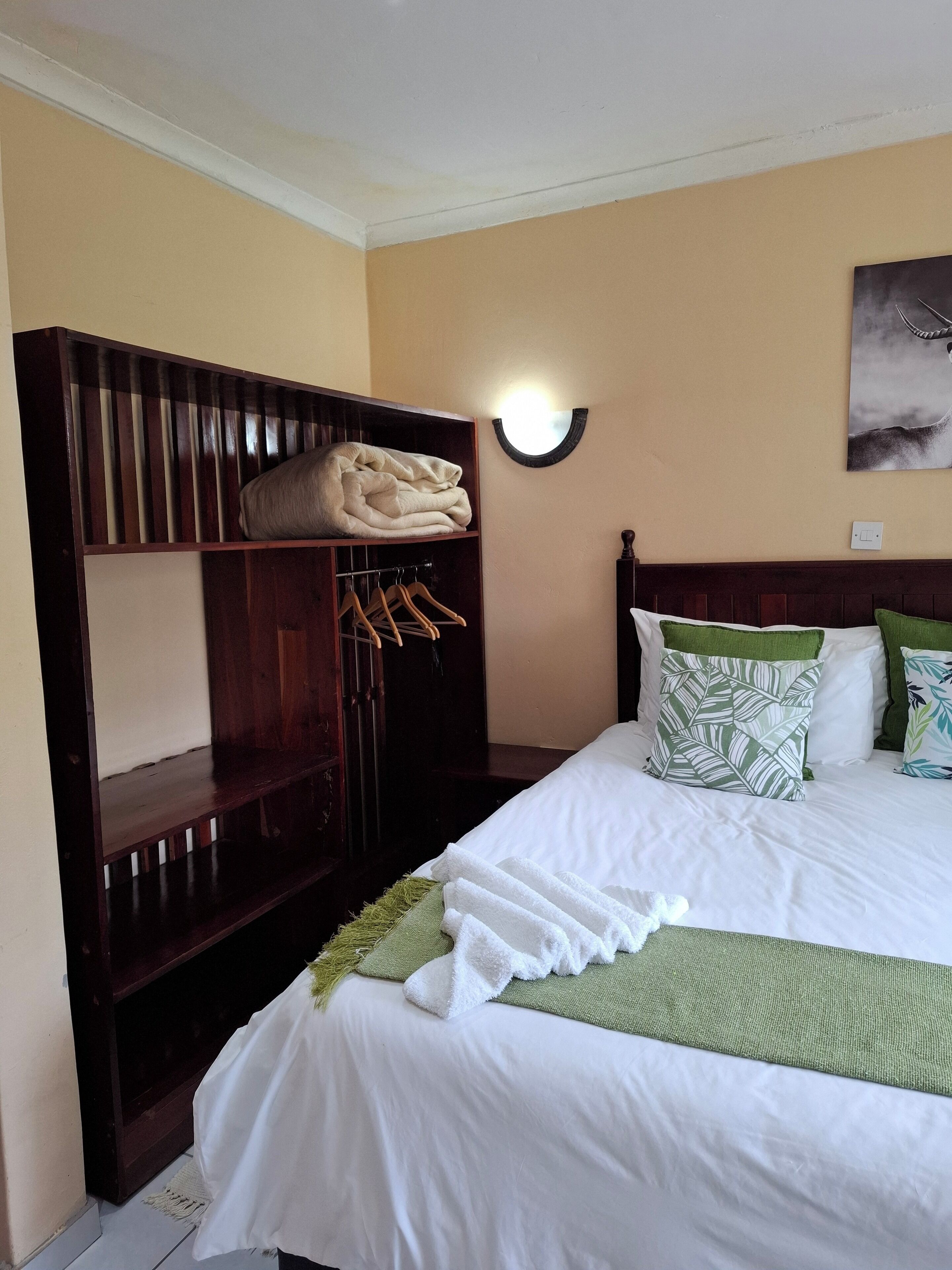 A hotel room with a bed, a wardrobe, and a wall-mounted light fixture.