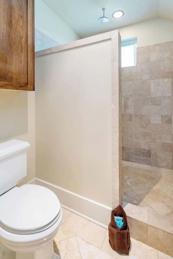 A bathroom with a toilet, shower, and a towel bag on the floor.