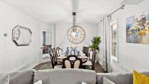 Una sala de estar moderna con un sofá gris, una zona de comedor con una mesa redonda y un cuadro abstracto grande en la pared.