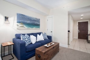 Relax in this stylish living room with a sofa, coffee table, and a beautiful coastal painting.