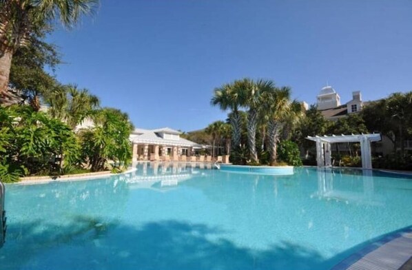 Relax by the tranquil pool surrounded by lush greenery and palm trees.