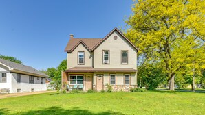 A two-story house with a front porch, a stone foundation, and a large tree with yellow leaves. - Dog-Friendly Watertown Vacation Rental w/ Deck (Watertown)