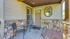 A covered porch with stone walls, a door, and two chairs. - Dog-Friendly Watertown Vacation Rental w/ Deck (Watertown)