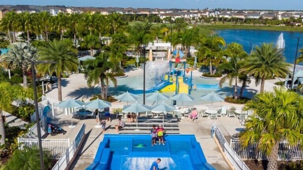 A water park with a large pool, slides, and palm trees.