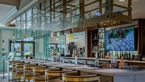 A bar area with a long counter, multiple stools, and a glass enclosure.
